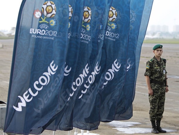 Một nhân viên an ninh ở sân bay Kiev bên những lá cờ chào mừng đến với EURO 2012.